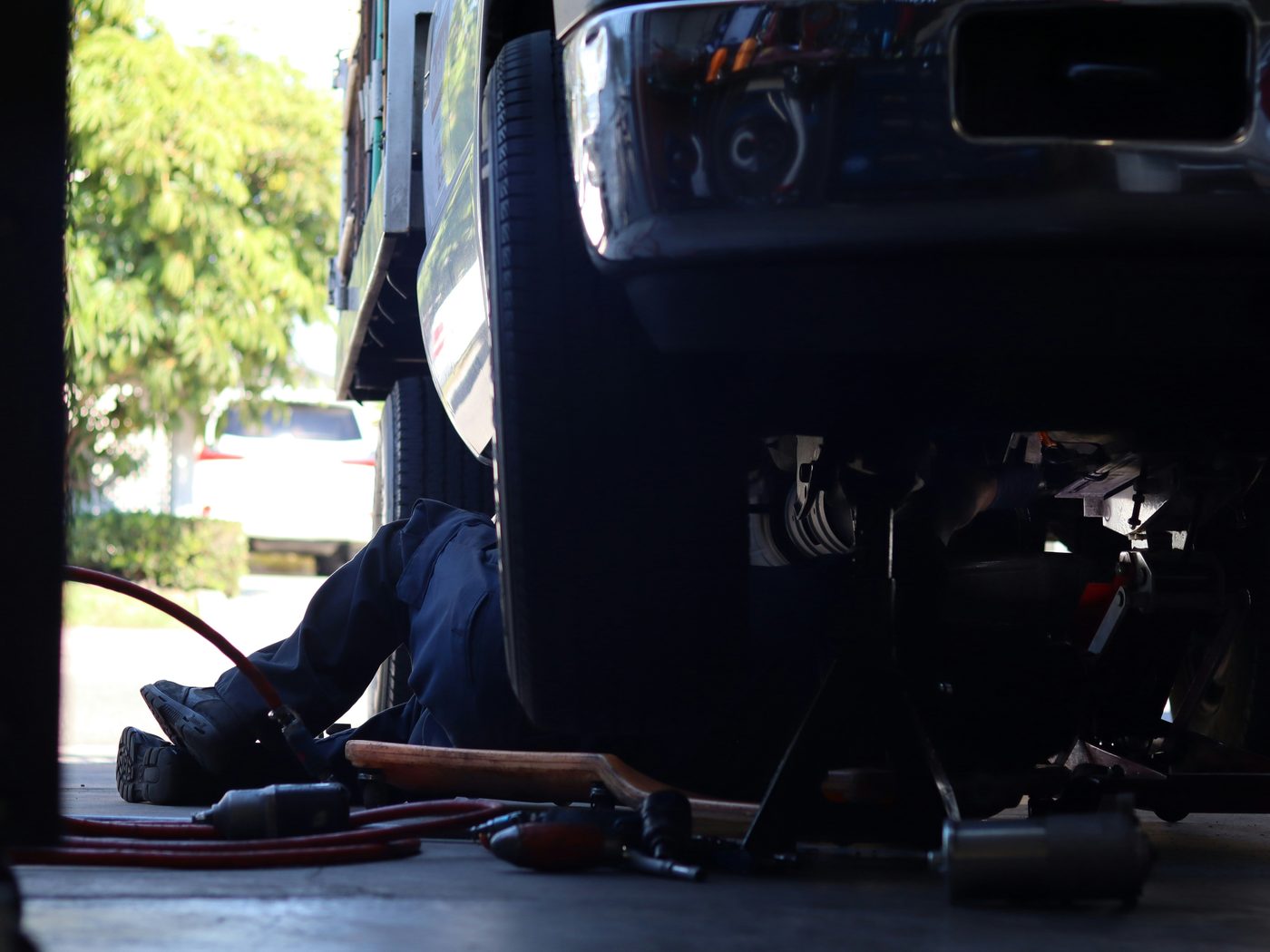 Technician working beneath a vehicle in a shop bay